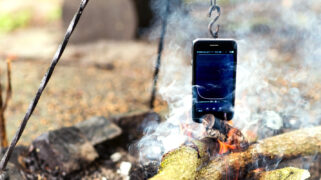 Een smartphone aan een hangijzer boven een vuurtje.