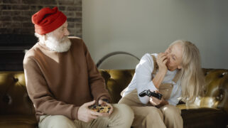 Twee oudere mensen op een bank spelen een game.